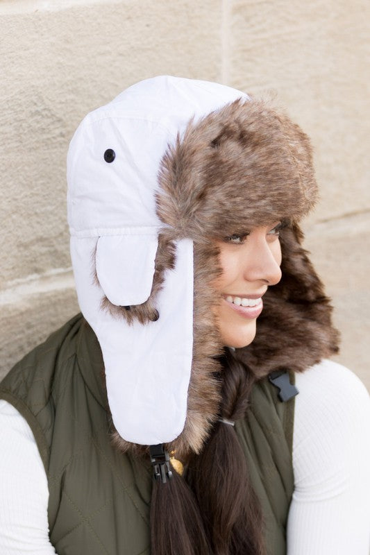 A woman smiling while adjusting a whimsical animal-themed Alpine Aviator Trapper hat.