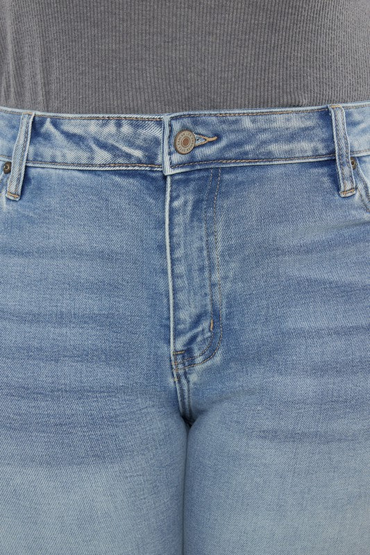 A person wearing a grey long-sleeve top and Plus Mid Rise Y2K Medium Wash Bootcut Jeans poses against a plain white background.