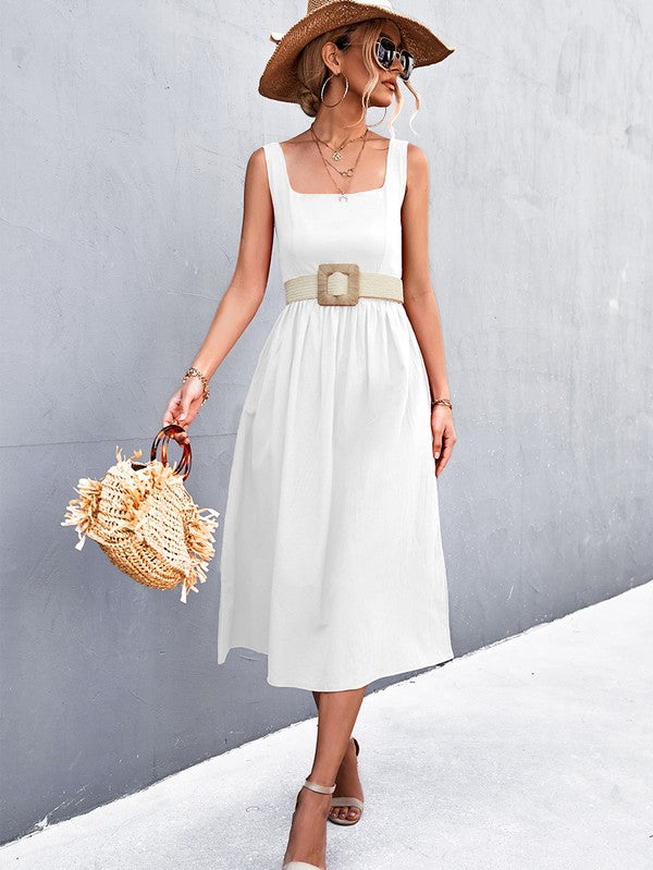 A woman in a Women's Sleeve Less Dress, featuring a vibrant red hue and crafted from 100% polyester, stands against a gray wall. She accessorizes with a wide-brimmed hat, holds a straw handbag, and complements her outfit with beige sandals.