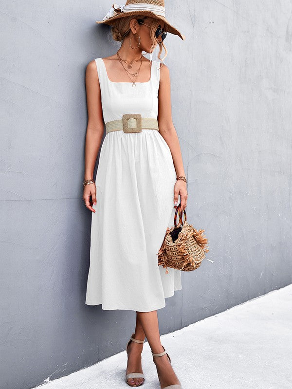 A woman in a Women's Sleeve Less Dress, featuring a vibrant red hue and crafted from 100% polyester, stands against a gray wall. She accessorizes with a wide-brimmed hat, holds a straw handbag, and complements her outfit with beige sandals.