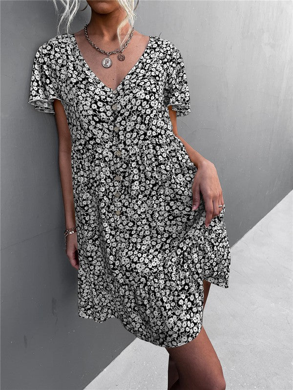 Individual wearing a Floral Short Sleeve V Neck Midi Length Dress stands against a gray wall.