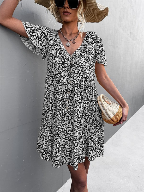 Individual wearing a Floral Short Sleeve V Neck Midi Length Dress stands against a gray wall.