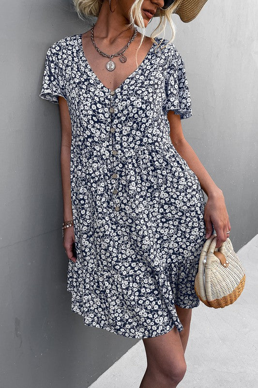 Individual wearing a Floral Short Sleeve V Neck Midi Length Dress stands against a gray wall.