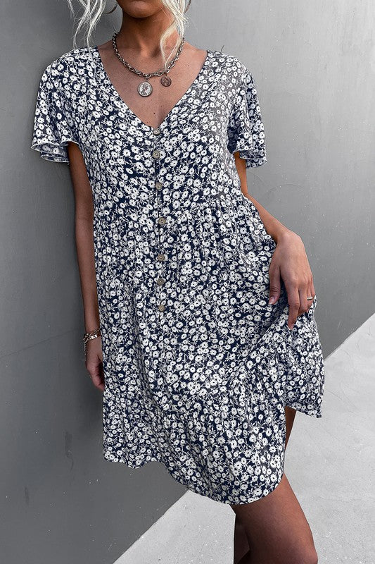 Individual wearing a Floral Short Sleeve V Neck Midi Length Dress stands against a gray wall.