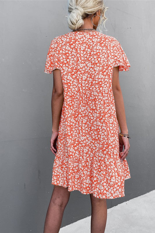 Individual wearing a Floral Short Sleeve V Neck Midi Length Dress stands against a gray wall.