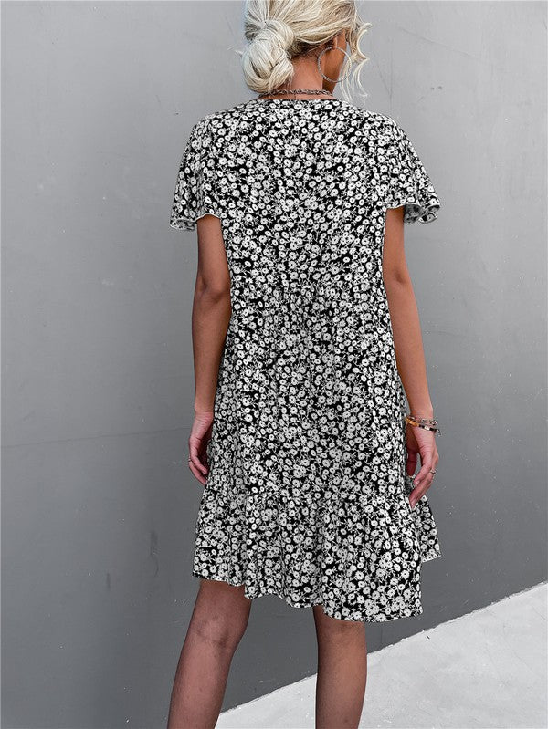 Individual wearing a Floral Short Sleeve V Neck Midi Length Dress stands against a gray wall.