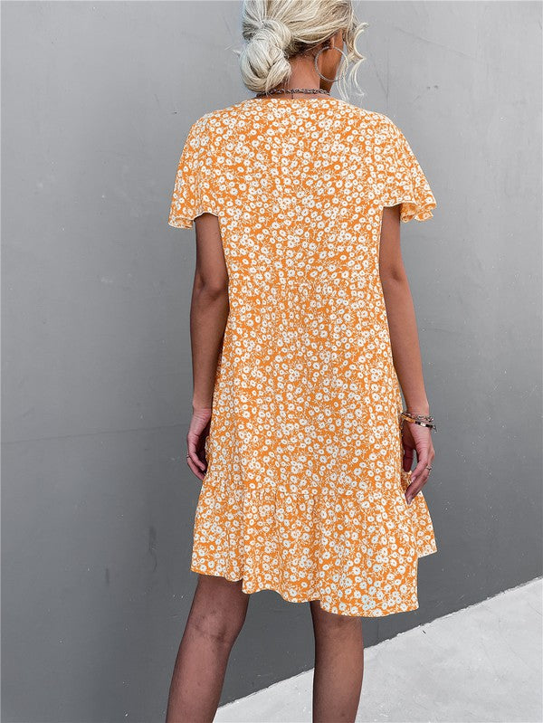 Individual wearing a Floral Short Sleeve V Neck Midi Length Dress stands against a gray wall.