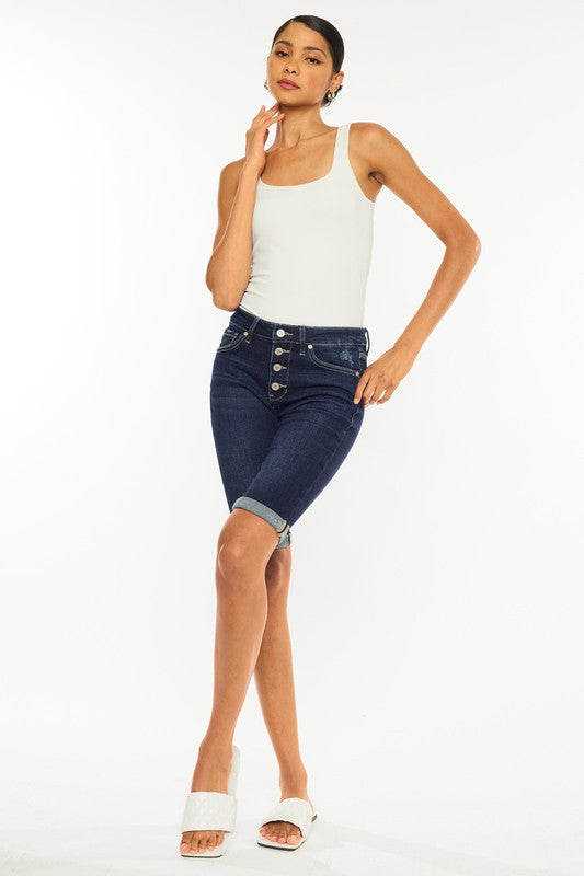 A woman wearing a white tank top and High Rise Button Down Cuffed Bermuda Jeans.