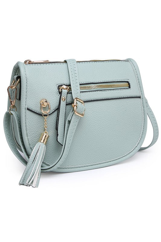 The Fashion Saddle Crossbody Bag in lavender faux vegan leather features a gold zipper, front pocket, tassel detail, and an adjustable shoulder strap.