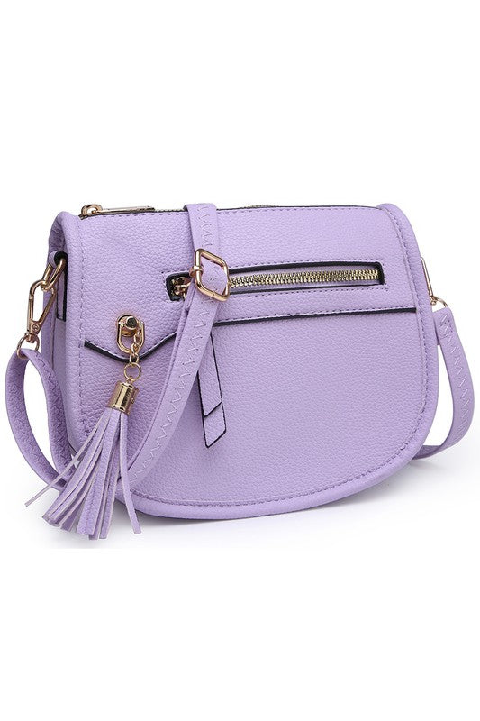 The Fashion Saddle Crossbody Bag in lavender faux vegan leather features a gold zipper, front pocket, tassel detail, and an adjustable shoulder strap.