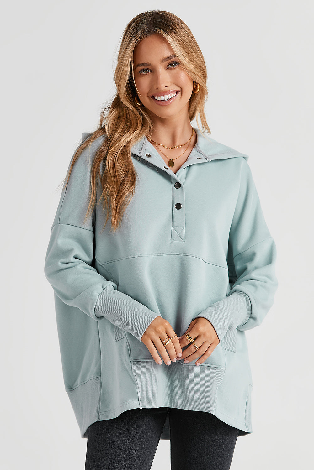 A person with long hair is smiling and looking over their shoulder while wearing a Gray Batwing Sleeve Pocketed Henley Hoodie.