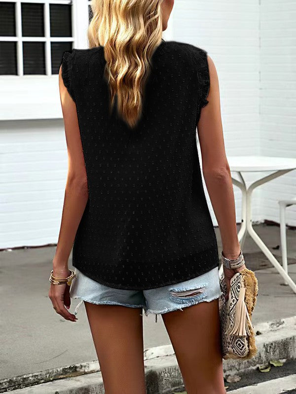 A woman wearing the Women Sleeveless Button Trim TOP, a white sleeveless top with button trim and ruffles made from 100% polyester, is paired with distressed denim shorts as she stands outside near a white building.