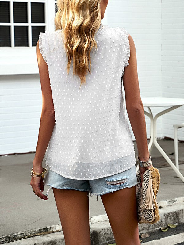 A woman wearing the Women Sleeveless Button Trim TOP, a white sleeveless top with button trim and ruffles made from 100% polyester, is paired with distressed denim shorts as she stands outside near a white building.