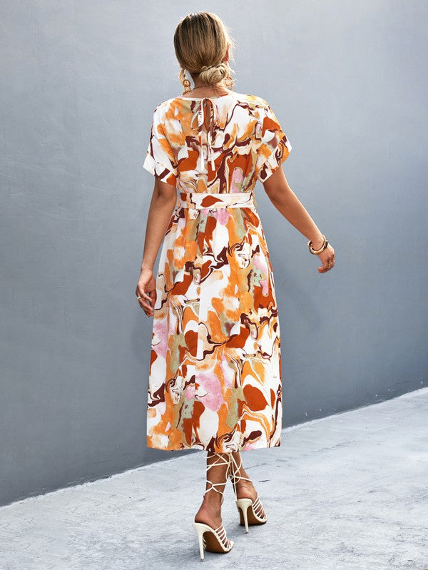 A woman in a Women Print Round Neck Short Sleeve Dress, complemented by a straw hat and sunglasses, gracefully strolls across a gray textured surface.