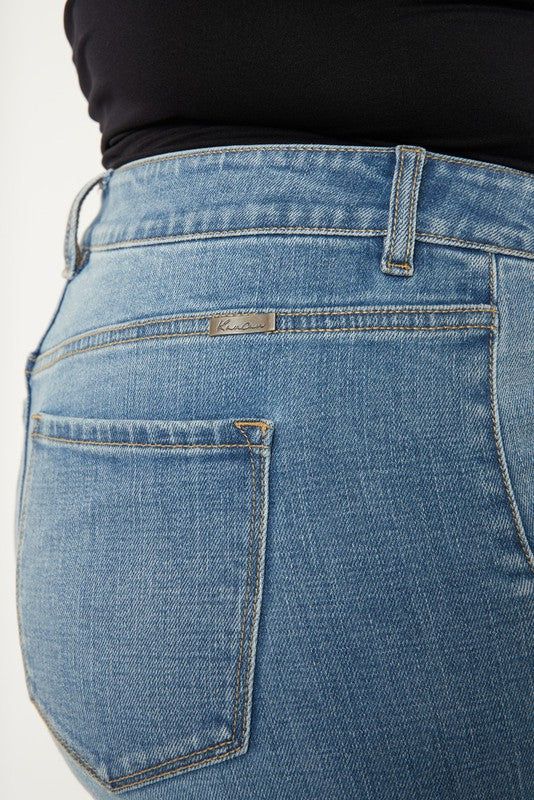 A person stands in a neutral pose, wearing a black sleeveless top, medium stone wash *Plus High Rise Trouser Wide Leg Jeans* made from comfort stretch denim, and black open-toe shoes, against a plain white background.