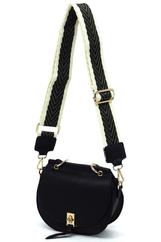The Fashion Flap Saddle Satchel Crossbody Bag is a light pink handbag crafted from faux vegan leather and adorned with gold hardware. It features a buckle clasp and comes with a detachable, wide strap that has a red and black chevron pattern with pink trim, allowing it to double as a chic crossbody bag.
