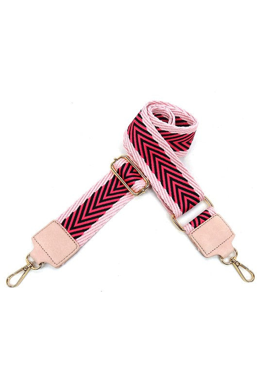 The Fashion Flap Saddle Satchel Crossbody Bag is a light pink handbag crafted from faux vegan leather and adorned with gold hardware. It features a buckle clasp and comes with a detachable, wide strap that has a red and black chevron pattern with pink trim, allowing it to double as a chic crossbody bag.