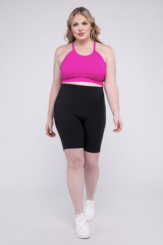 Against a plain background, a person showcases the Plus Athletic High Rise Biker Shorts in coral, crafted from high-quality athletic fabric and paired with a pink top.