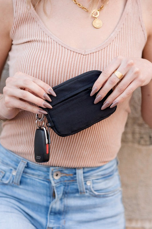 A person holds the Journey Clippable ID Wallet Pouch, featuring a sleek black design crafted from water-resistant nylon, with an ID card cleverly clipped and car keys securely attached.