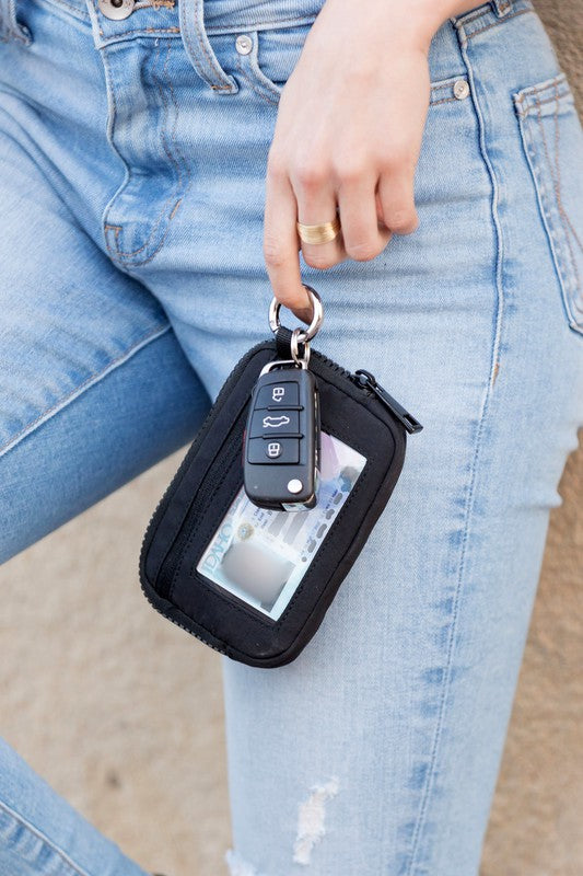 A person holds the Journey Clippable ID Wallet Pouch, featuring a sleek black design crafted from water-resistant nylon, with an ID card cleverly clipped and car keys securely attached.