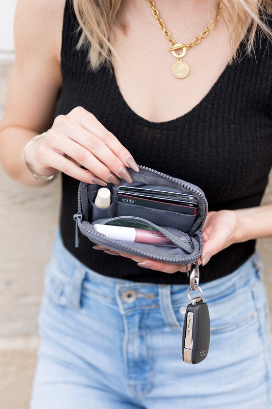 A person holds the Journey Clippable ID Wallet Pouch, featuring a sleek black design crafted from water-resistant nylon, with an ID card cleverly clipped and car keys securely attached.