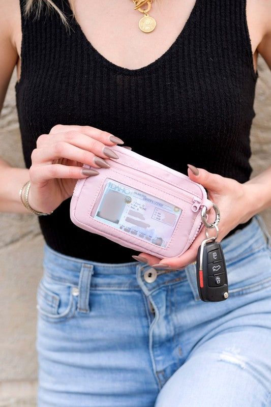 A person holds the Journey Clippable ID Wallet Pouch, featuring a sleek black design crafted from water-resistant nylon, with an ID card cleverly clipped and car keys securely attached.