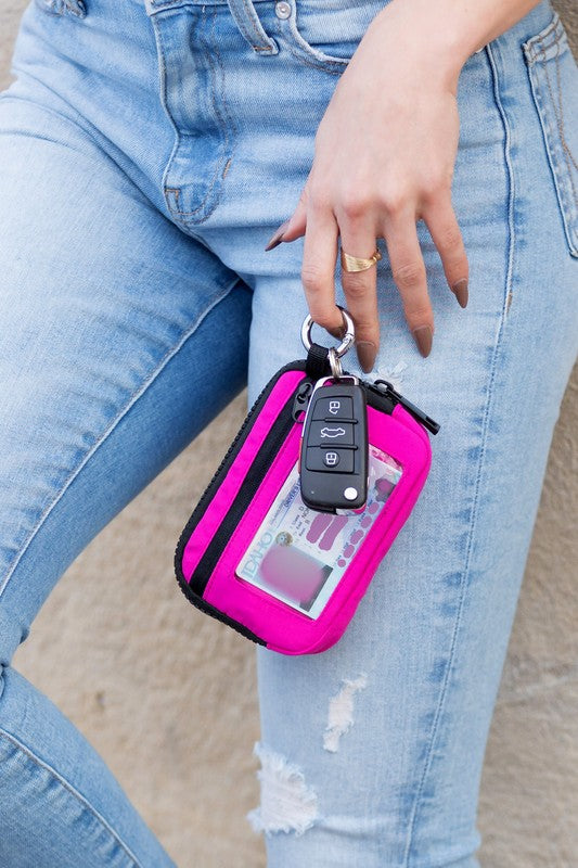 A person holds the Journey Clippable ID Wallet Pouch, featuring a sleek black design crafted from water-resistant nylon, with an ID card cleverly clipped and car keys securely attached.