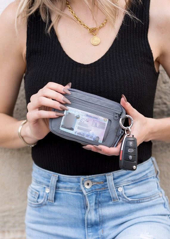 A person holds the Journey Clippable ID Wallet Pouch, featuring a sleek black design crafted from water-resistant nylon, with an ID card cleverly clipped and car keys securely attached.