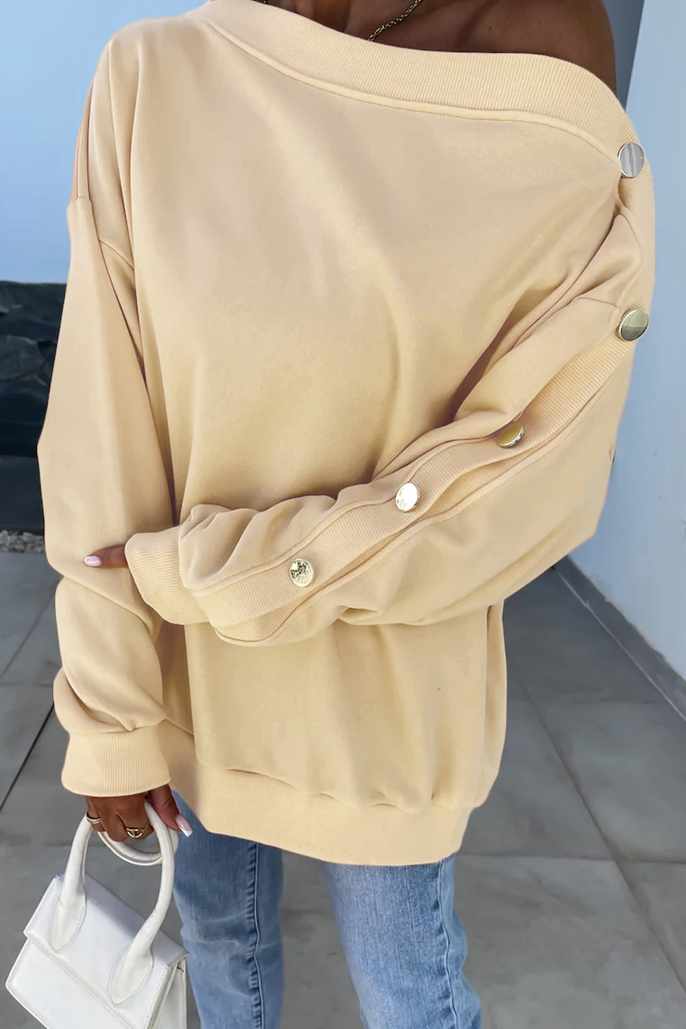 Woman with long wavy hair wearing the Beige Buttoned Sleeve Dropped Shoulder Sweatshirt, standing in a bright indoor setting.