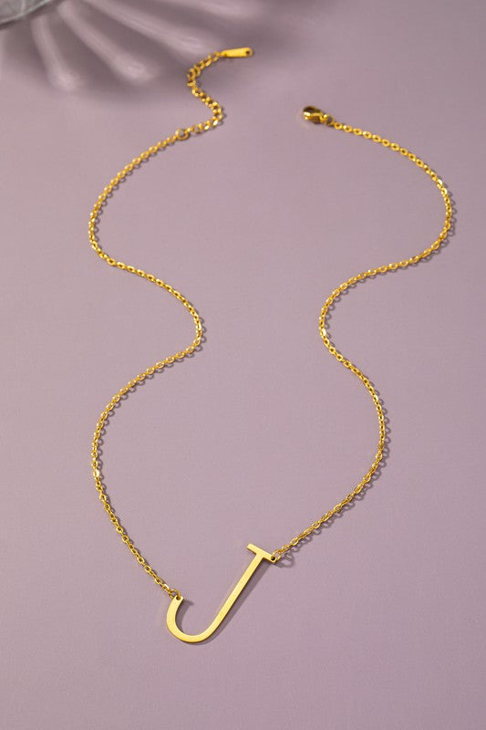 The Large Stainless Steel Initial Pendant Necklace features gold necklaces with prominent, capital letters "A," "B," and "C" set against a vibrant purple background, forming a stunning collection of initial pendants. Crafted from high-quality stainless steel, these pieces offer both durability and style.