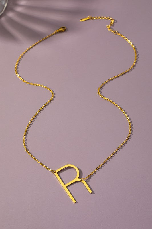 The Large Stainless Steel Initial Pendant Necklace features gold necklaces with prominent, capital letters "A," "B," and "C" set against a vibrant purple background, forming a stunning collection of initial pendants. Crafted from high-quality stainless steel, these pieces offer both durability and style.