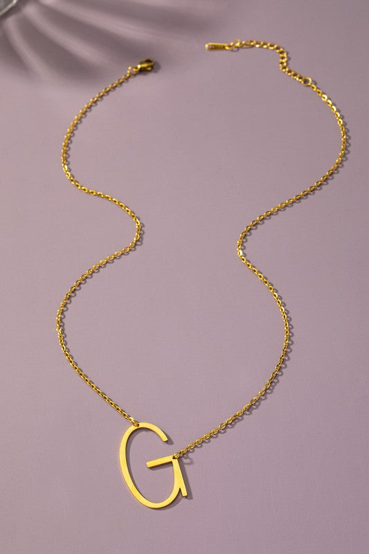 The Large Stainless Steel Initial Pendant Necklace features gold necklaces with prominent, capital letters "A," "B," and "C" set against a vibrant purple background, forming a stunning collection of initial pendants. Crafted from high-quality stainless steel, these pieces offer both durability and style.