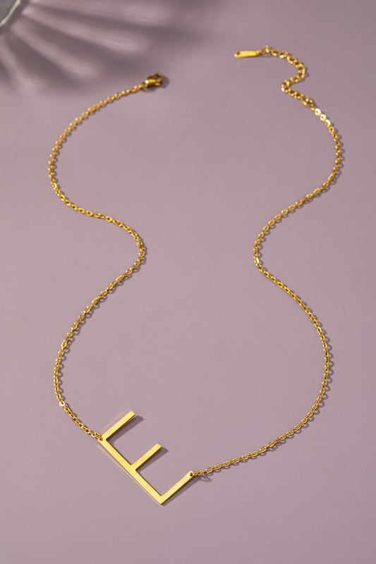 The Large Stainless Steel Initial Pendant Necklace features gold necklaces with prominent, capital letters "A," "B," and "C" set against a vibrant purple background, forming a stunning collection of initial pendants. Crafted from high-quality stainless steel, these pieces offer both durability and style.