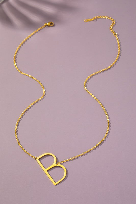 The Large Stainless Steel Initial Pendant Necklace features gold necklaces with prominent, capital letters "A," "B," and "C" set against a vibrant purple background, forming a stunning collection of initial pendants. Crafted from high-quality stainless steel, these pieces offer both durability and style.