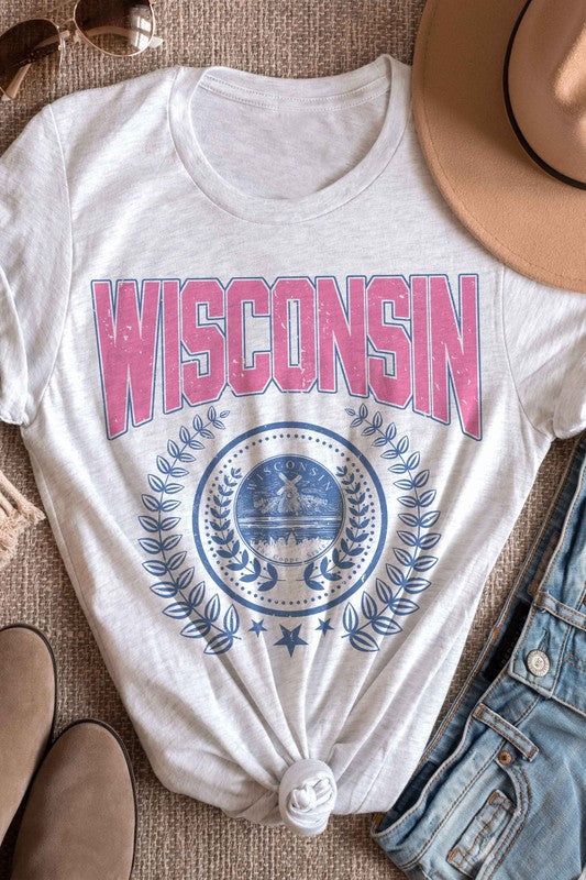 A person wearing a 100% cotton WISCONSIN GRAPHIC TEE, featuring the word "Wisconsin" in pink letters and a blue emblem with laurel wreaths underneath, designed for unisex sizing to fit everyone.