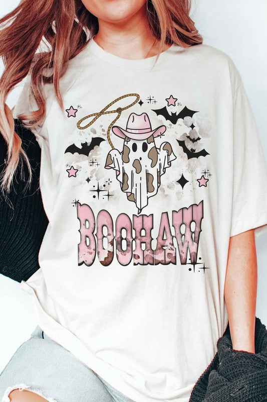 A person wearing a unisex BOOHAW COWBOY GHOST GRAPHIC TEE, made of 100% cotton, featuring a graphic of a Cowboy Ghost in a white T-shirt and the word "BOOHAW" in pink western-style lettering.