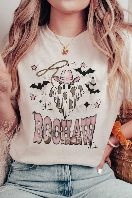 A person wearing a unisex BOOHAW COWBOY GHOST GRAPHIC TEE, made of 100% cotton, featuring a graphic of a Cowboy Ghost in a white T-shirt and the word "BOOHAW" in pink western-style lettering.