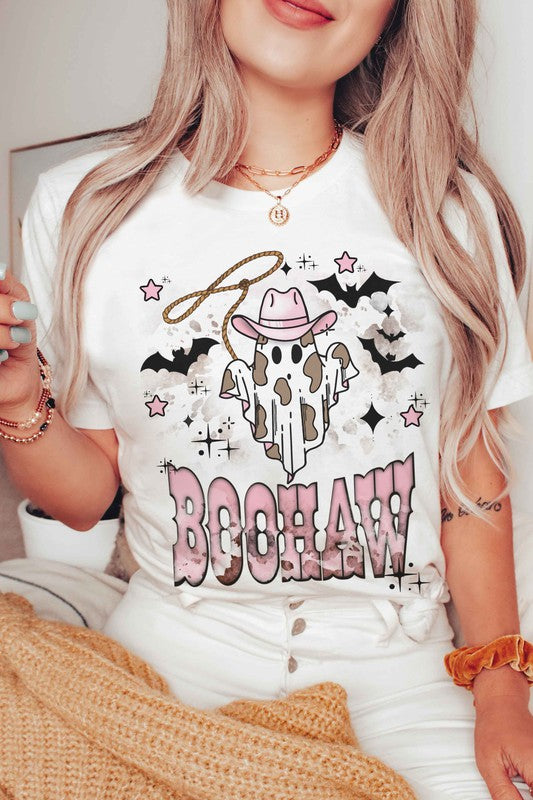 A person wearing a unisex BOOHAW COWBOY GHOST GRAPHIC TEE, made of 100% cotton, featuring a graphic of a Cowboy Ghost in a white T-shirt and the word "BOOHAW" in pink western-style lettering.