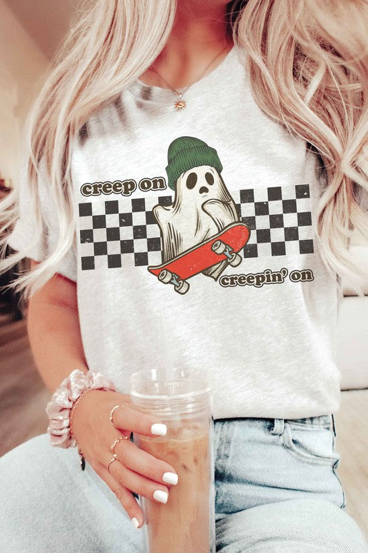 Wearing the "CREEP ON CREEPIN' ON" graphic tee, which is a 100% cotton white t-shirt featuring a ghost on a skateboard with the text "creep on creepin' on," the person holds an iced coffee.