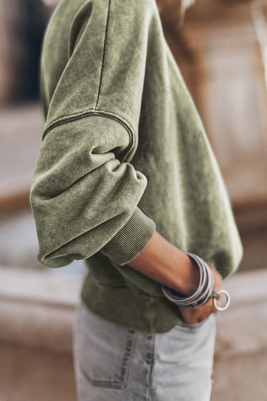 A person wearing a Mineral Washed Acid dye Sweatshirt Pullover with a drop shoulder design and distressed denim shorts stands with hands in pockets.