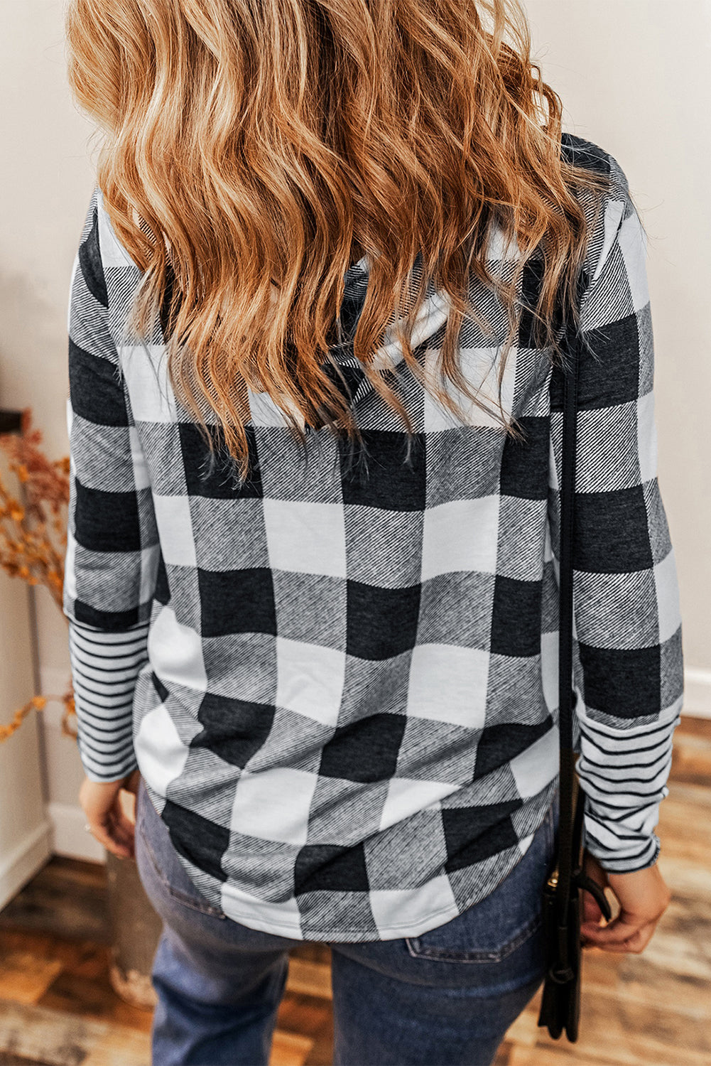 A person with wavy hair wearing a Multicolour Plaid Striped Patchwork Drawstring Hoodie stands indoors, facing away from the camera.