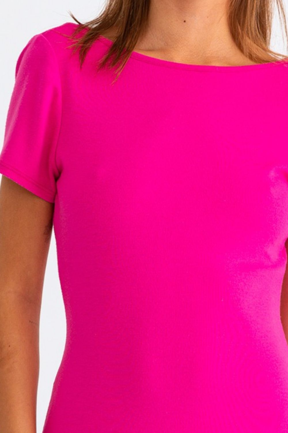 A person stands against a plain white background, wearing the Le Lis Short Sleeve Low Back Mini Dress in bright pink.