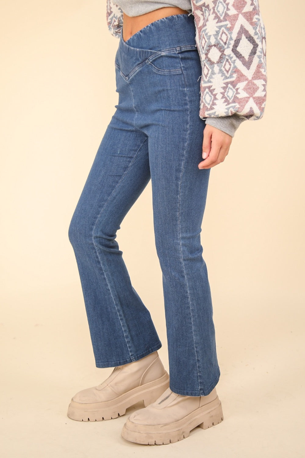 Person wearing VERY J Washed Denim Stretchy Crossover Waist Leggings with a hint of flared leg, and beige ankle-length boots. Only the lower half of the body is visible.