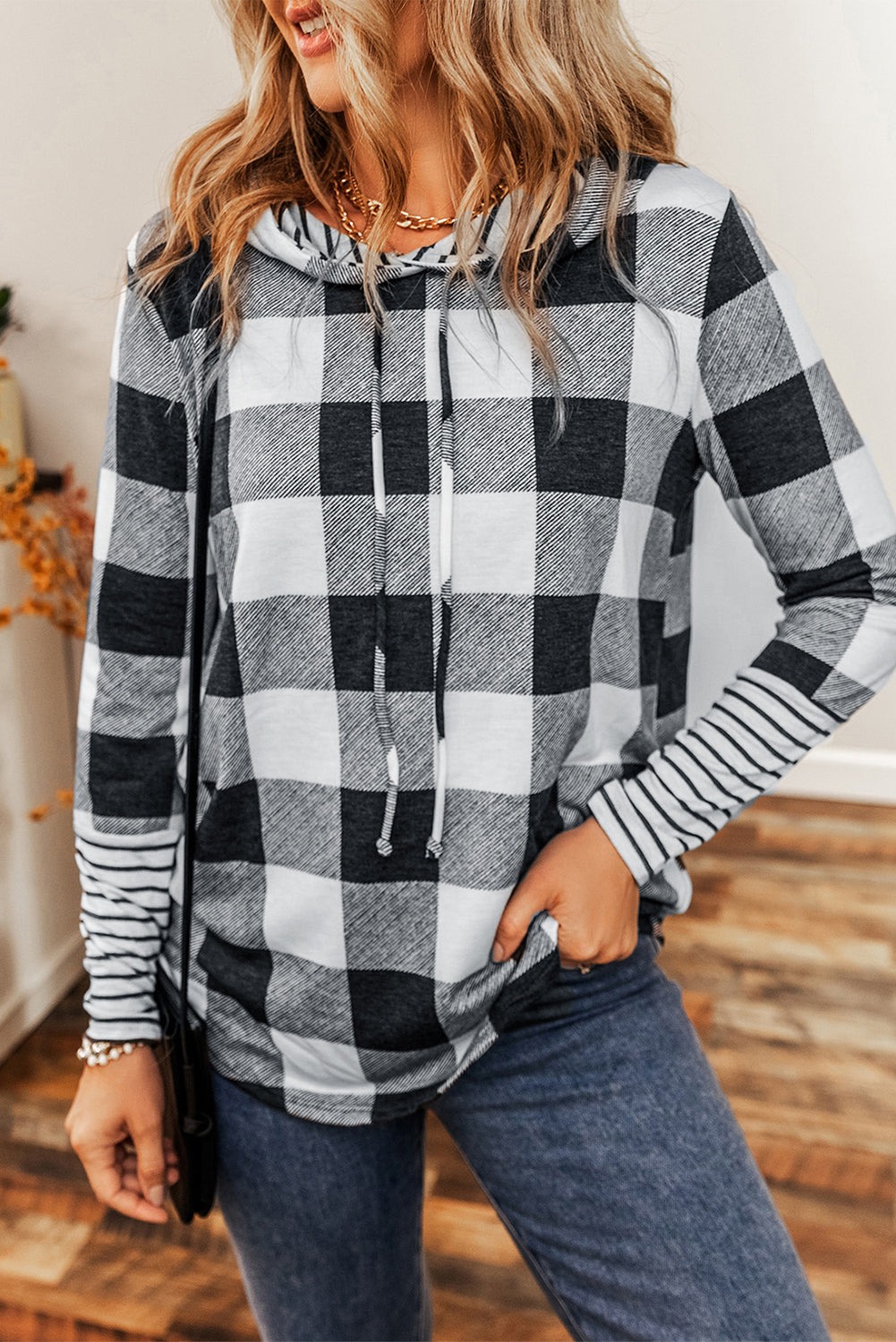 A person with wavy hair wearing a Multicolour Plaid Striped Patchwork Drawstring Hoodie stands indoors, facing away from the camera.