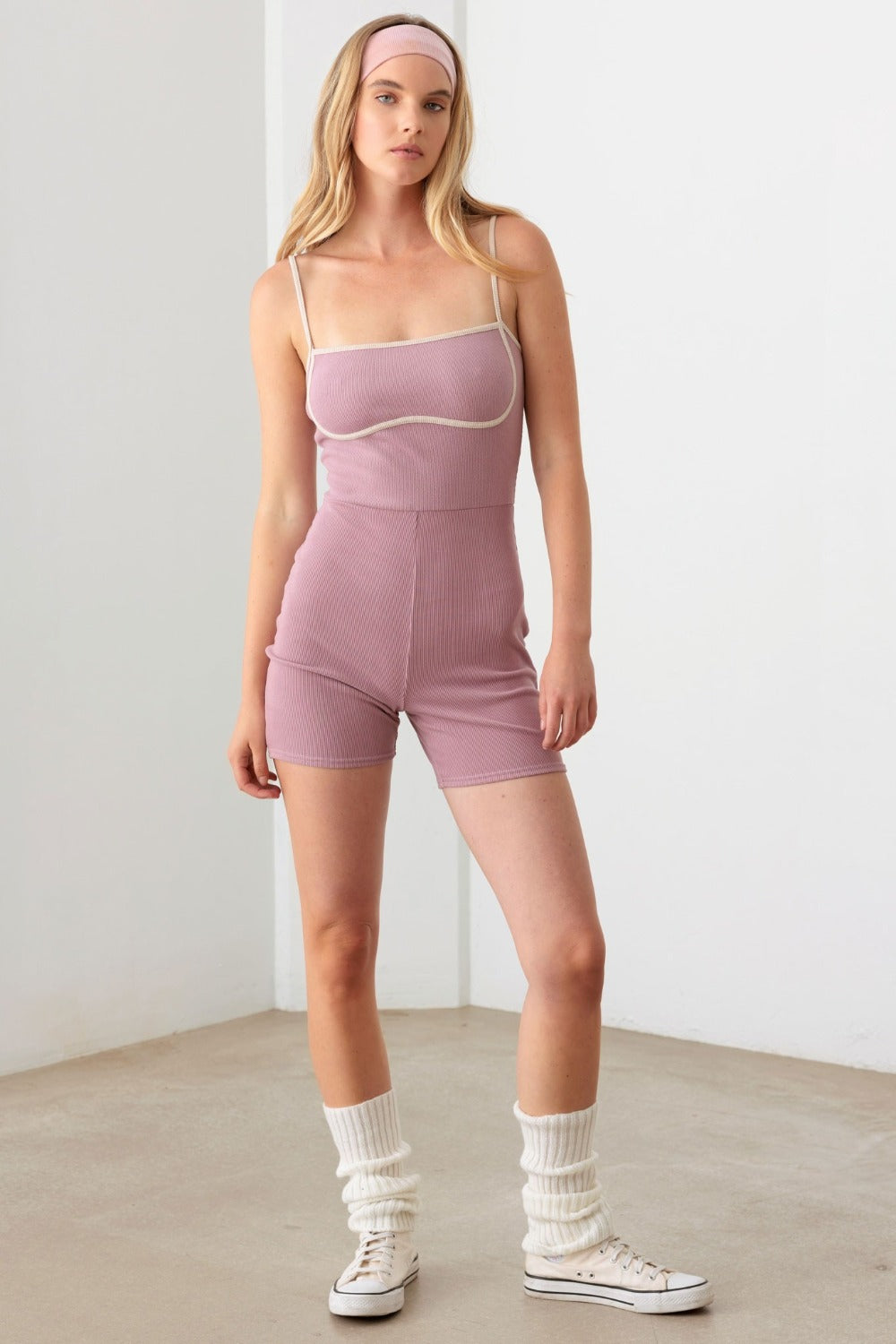 A person standing indoors wears the Le Lis Contrast Trim Ribbed Knit Bodycon Romper and a matching headband.