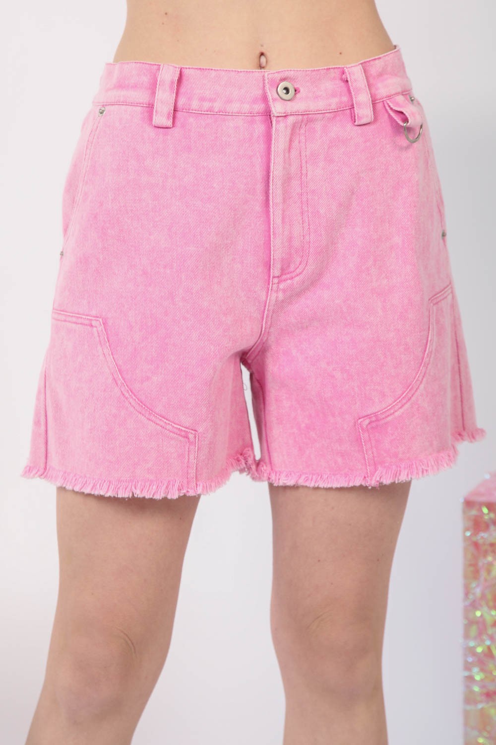 A person embodies the essence of summer fashion in the VERY J Washed Raw Hem Denim Shorts, featuring chic frayed hems and practical front pockets.