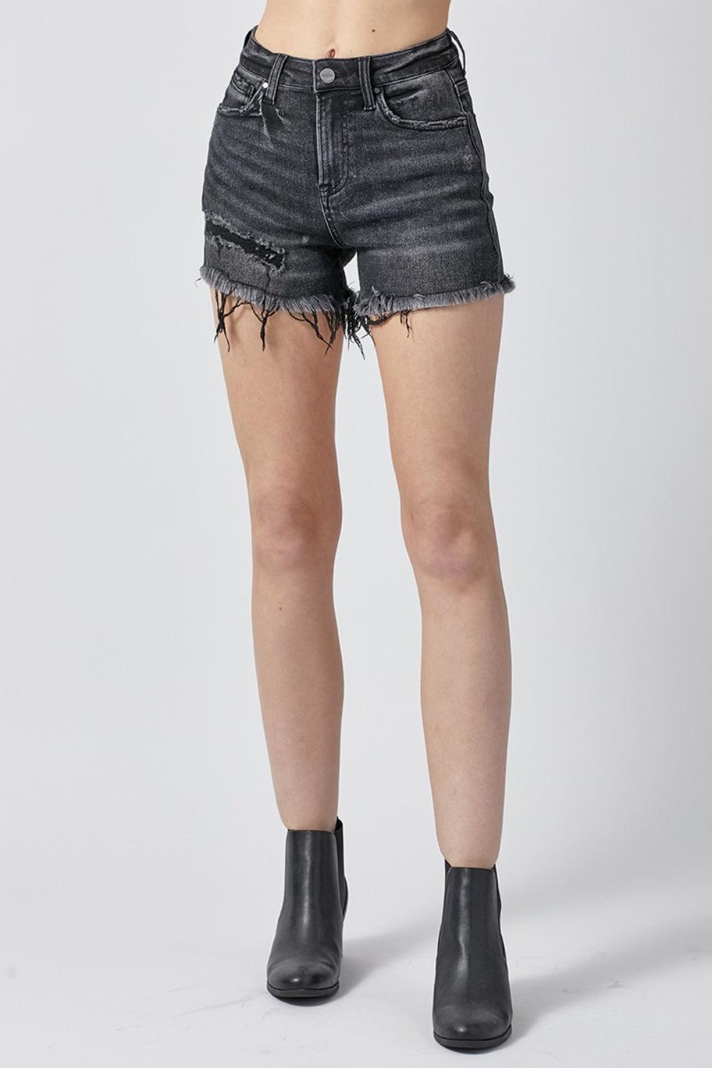 A person wearing RISEN Raw Hem Denim Shorts with Pockets, featuring high-waisted, distressed black design and a button and zipper closure, perfect for summer outfits.