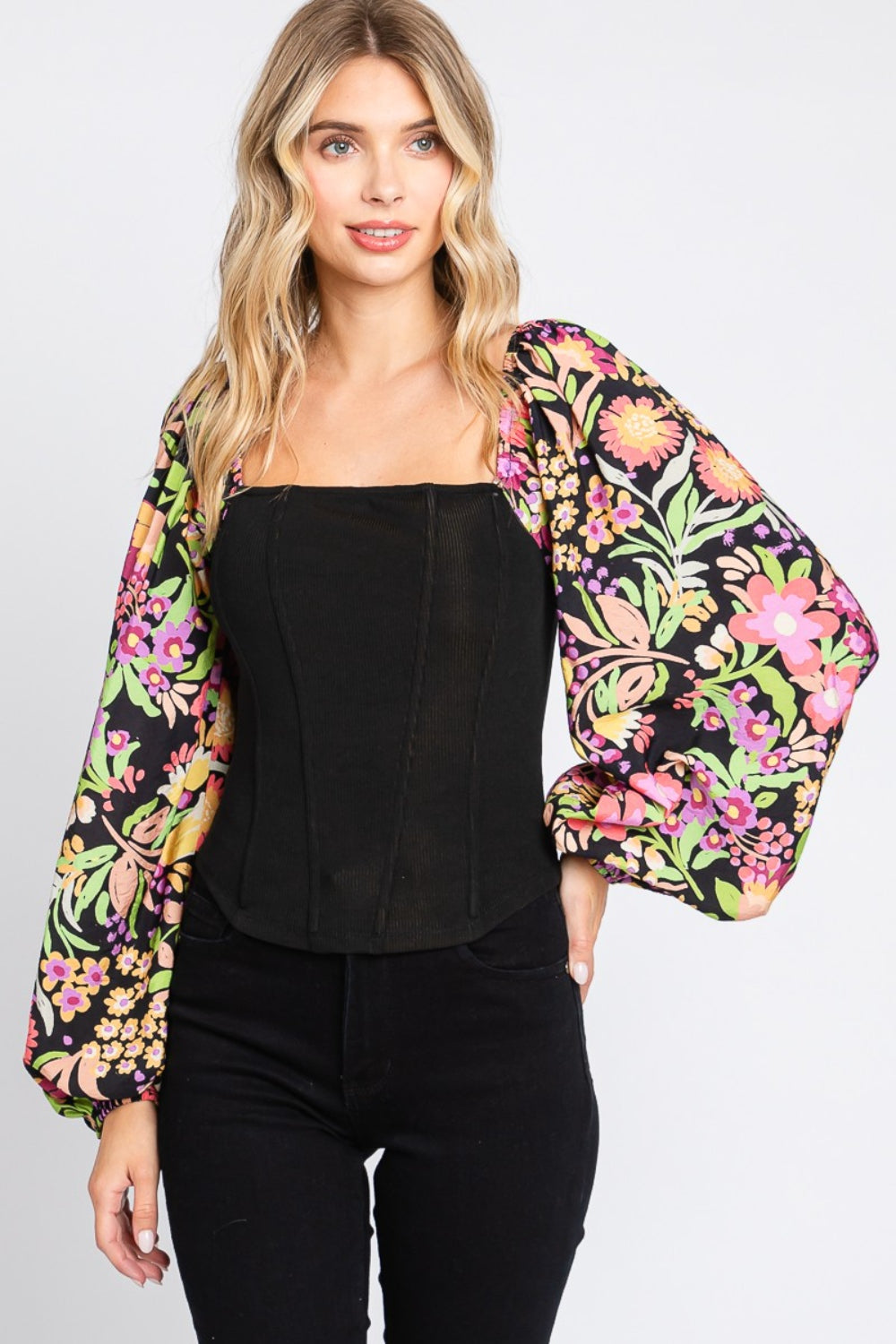 A woman wearing the chic ODDI Full Size Floral Balloon Sleeve Blouse poses against a plain background, showcasing this versatile piece.