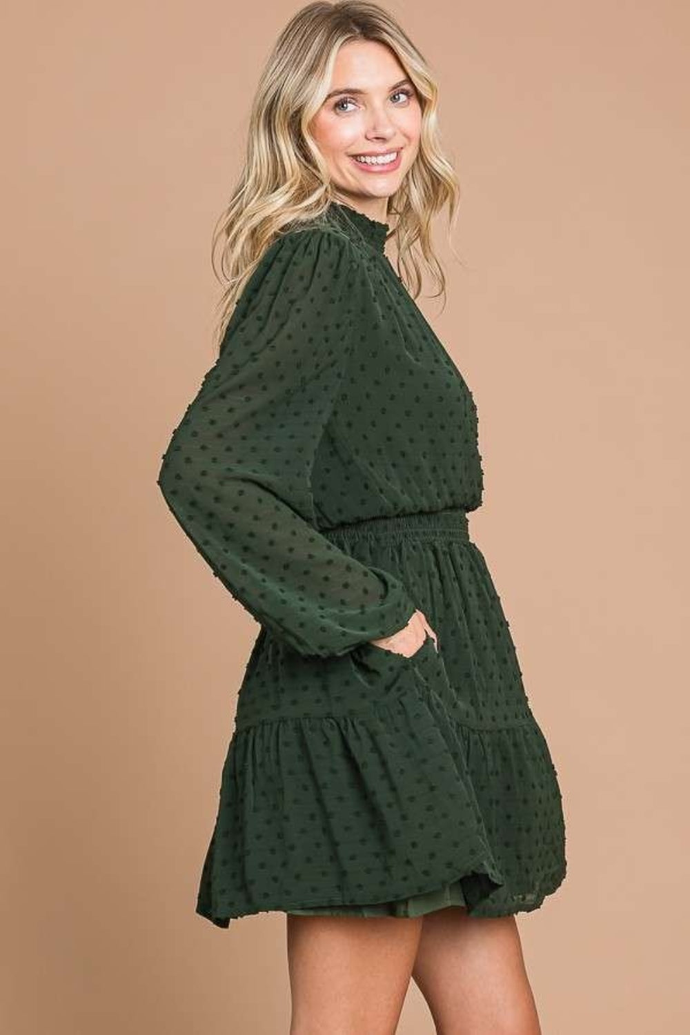 Draped gracefully, a woman wears the Culture Code Swiss Dot Smock Neck Mini Dress with Pockets in green crinkle chiffon.