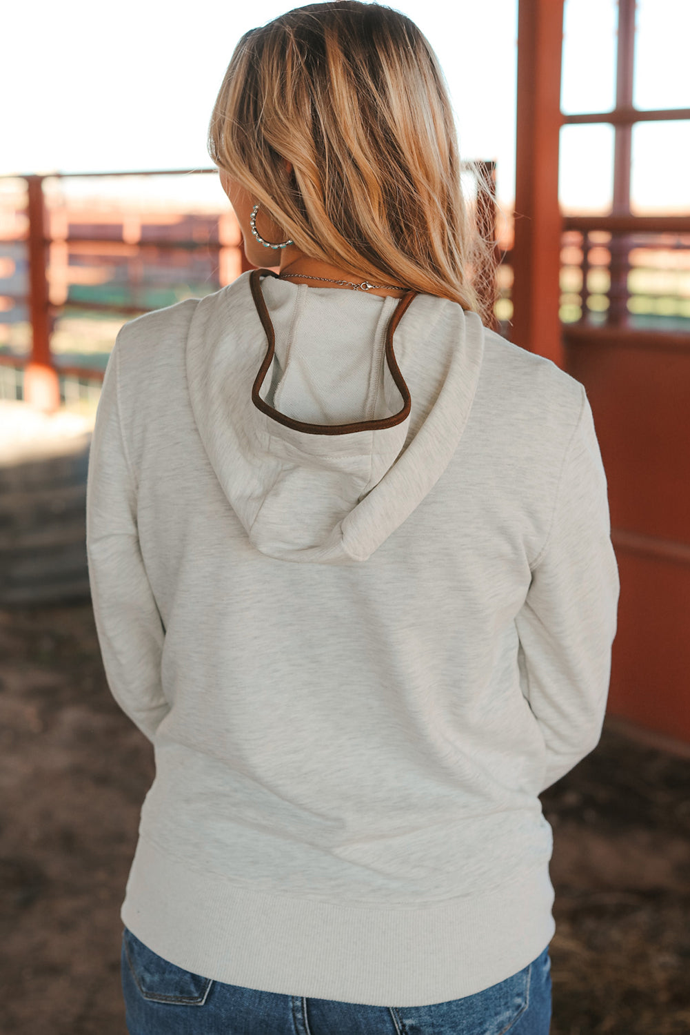 A person with long blonde hair is seen from the back wearing a Beige Drawstring Kangaroo Pocket Henley Hoodie and jeans.